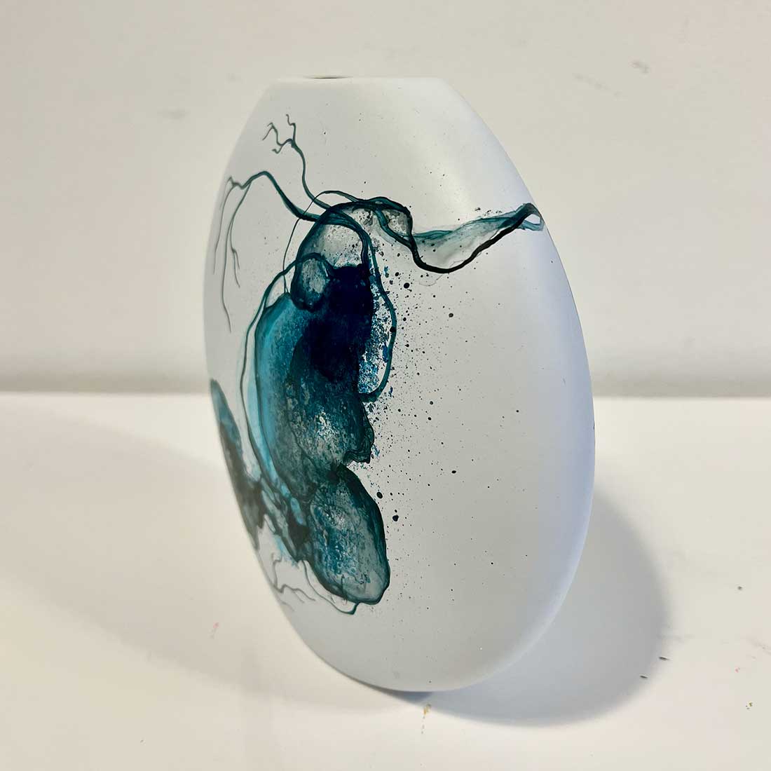 Hvid vase med abstrakt kunst i blå. Kunstner Rikke Darling