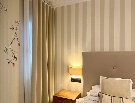 Vægmaleri i soveværelse. Indretning af lyst beige hotelværelse med botanisk kunst. 