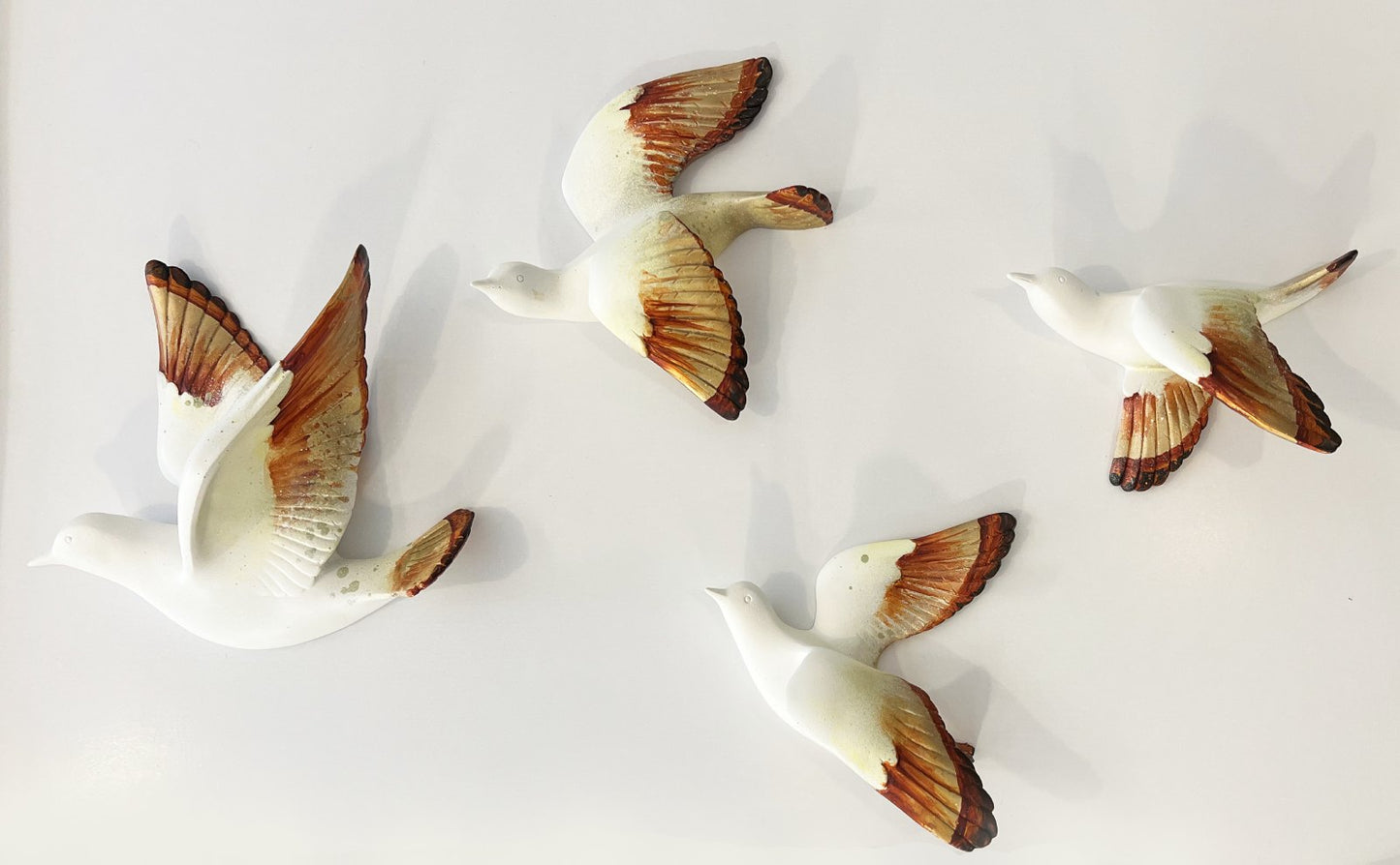 Fugleflok på væggen som vægskulptur i orange og guld af kunstner Rikke Darling